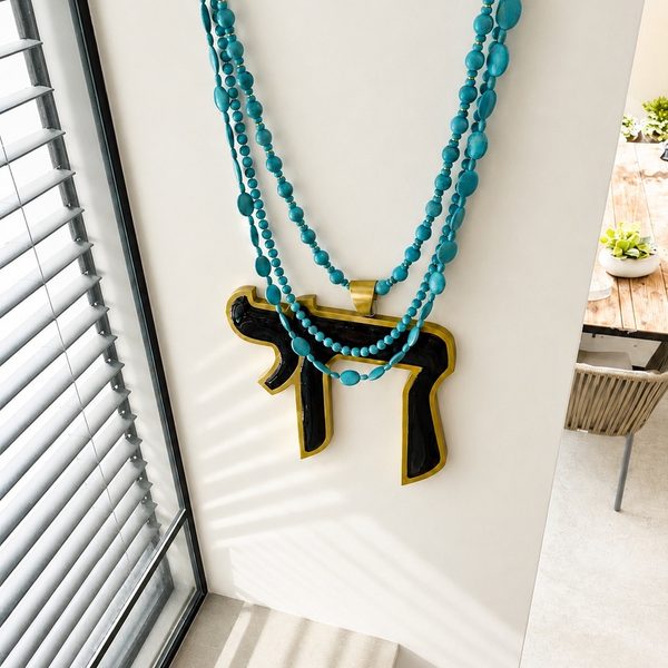 HAI in deep green enamel and gold on a sunlit wall beside a balcony