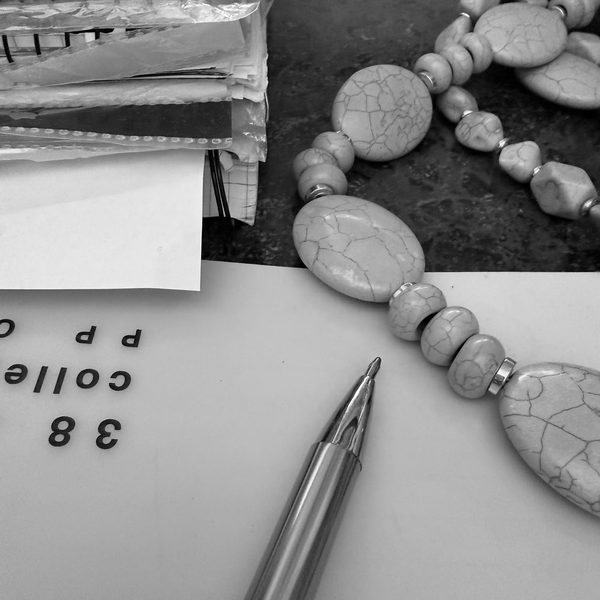 A turquoise bead necklace being knotted by hand on the workbench