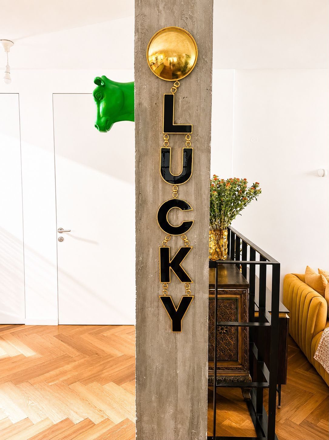 LUCKY WALL PENDANT, black enamel letters and brass on a concrete column